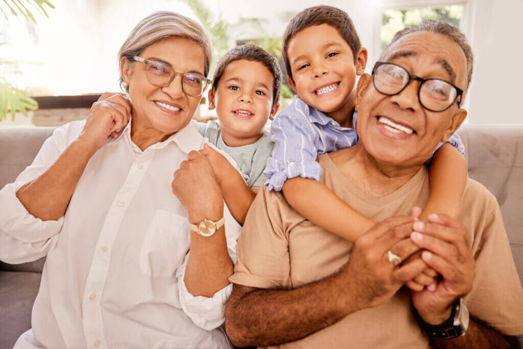 Familia de migrantes sonriendo a la cámara. Nietos y abuelos abrazados.